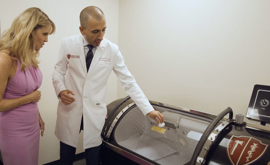 Dr. Babak Hajhosseini, world-renowned physician-scientist and founder, instructing a patient on the Hyperbaric Oxygen Therapy in Los Angeles.